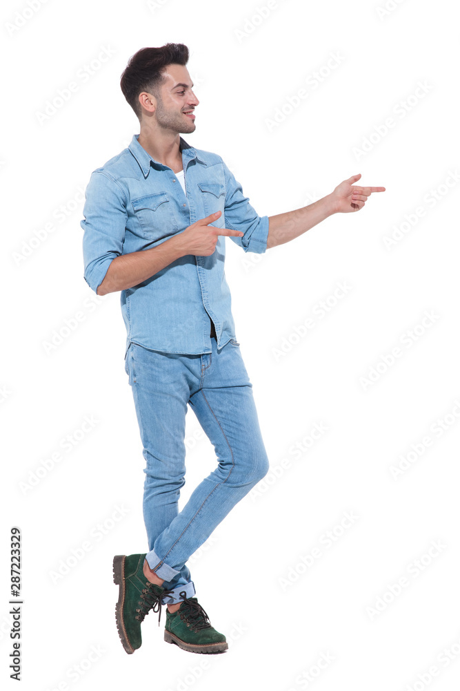 relaxed young man greeting and pointing fingers to side relaxed young man greeting and pointing fingers to side