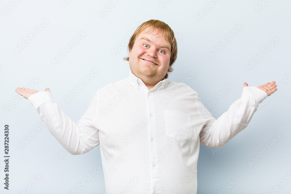Young authentic redhead fat man makes scale with arms, feels happy and confident. Young authentic redhead fat man makes scale with arms, feels happy and confident.
