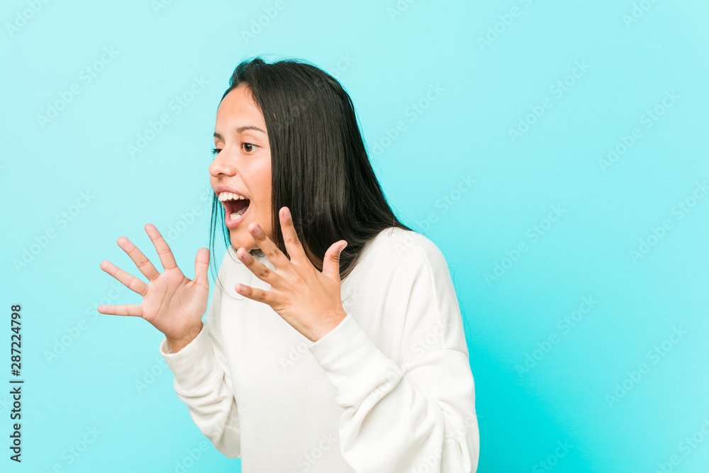 Young pretty hispanic woman shouts loud, keeps eyes opened and hands tense. Young pretty hispanic woman shouts loud, keeps eyes opened and hands tense.