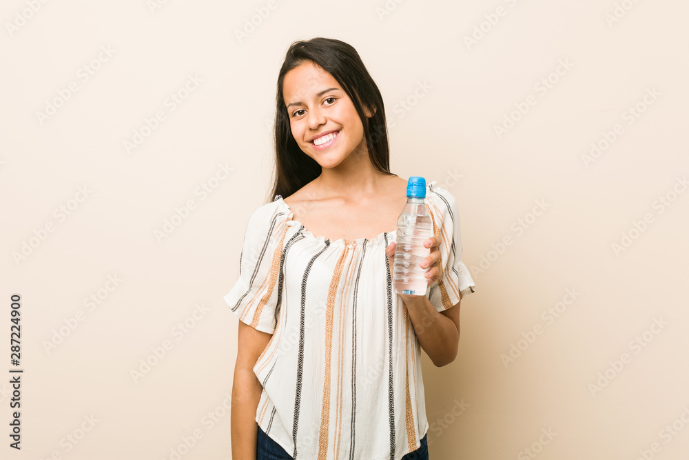 Young hispanic woman holding a bottle of water happy, smiling and cheerful. Young hispanic woman holding a bottle of water happy, smiling and cheerful.