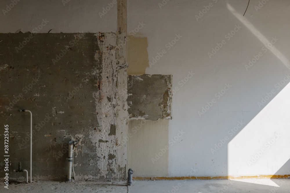 Interior view of old crack damaged white wall. Abandon empty room. Indoor space of renovating construction site. 