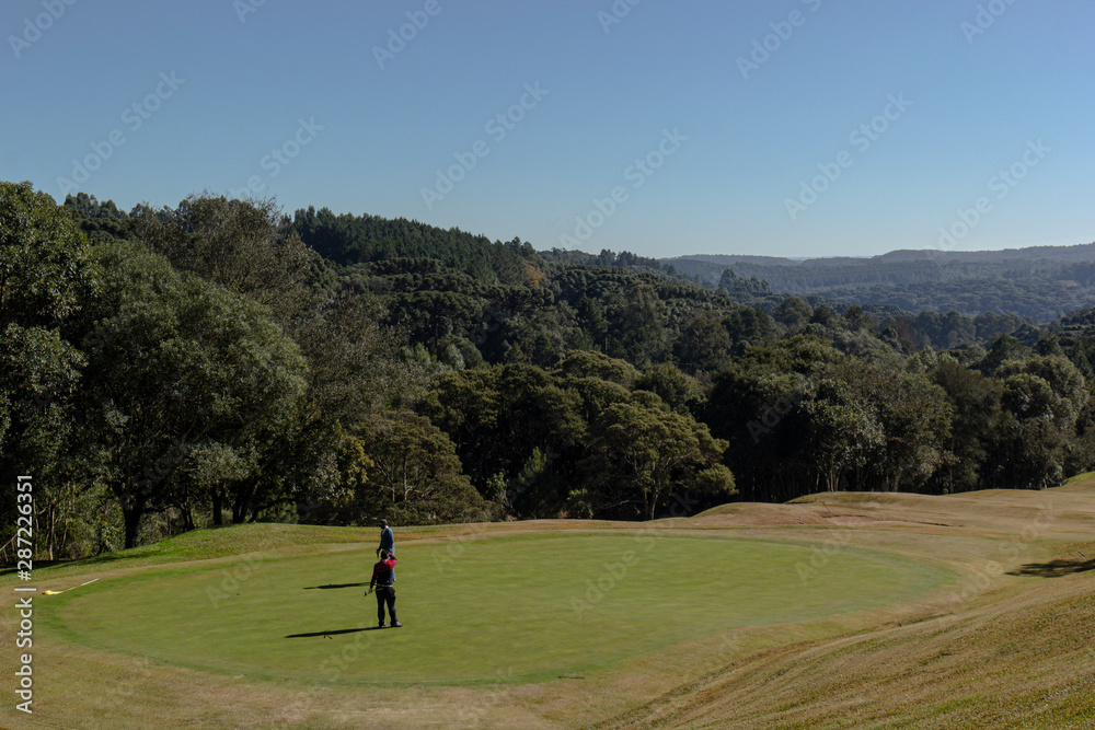 Pessoas jogando golfe no campo de golfe com árvores e céu azul Pessoas jogando golfe no campo de golfe com árvores e céu azul