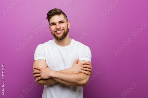 Young handsome caucasian man who feels confident, crossing arms with determination.
