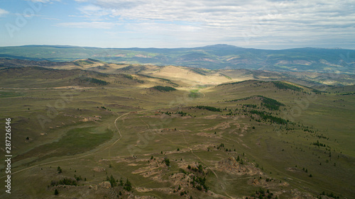 Baikal region. Dirt road on Tazheranskaya steppe near the stone rocks, called the Valley of the Stone Spirits. Aerial photo