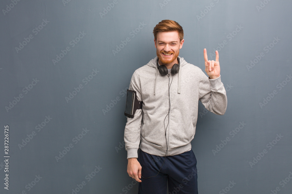 Young fitness redhead man doing a rock gesture