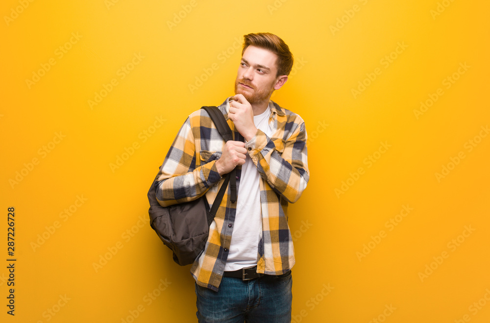 Young redhead student man doubting and confused Young redhead student man doubting and confused