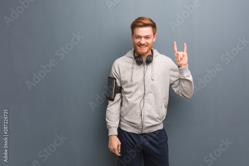 Young fitness redhead man doing a rock gesture © Asier