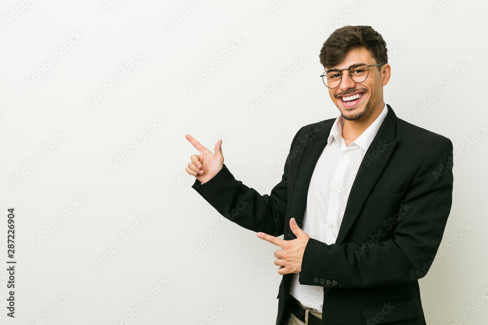 Young business hispanic man pointing with forefingers to a copy space, expressing excitement and desire. Young business hispanic man pointing with forefingers to a copy space, expressing excitement and desire.