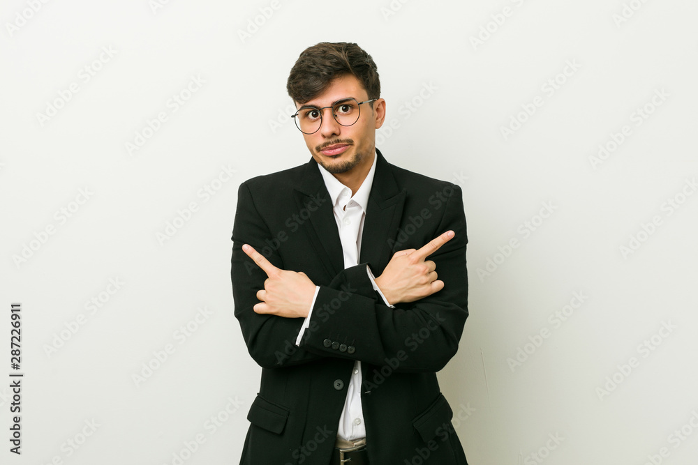 Young business hispanic man points sideways, is trying to choose between two options. Young business hispanic man points sideways, is trying to choose between two options.