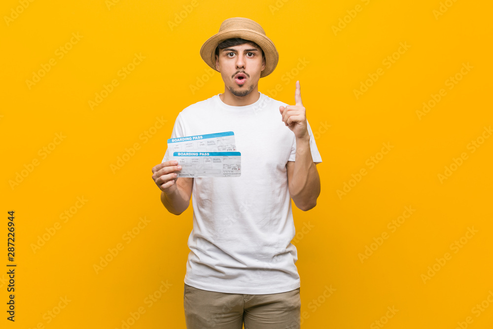 Young hispanic man holding an air tickets having some great idea, concept of creativity.