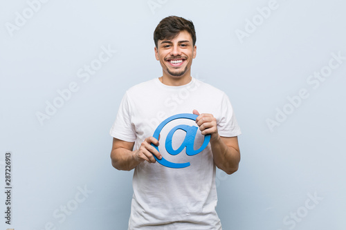 Young hispanic man holding at icon happy, smiling and cheerful.