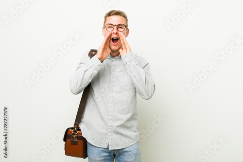 Young caucasian business man shouting excited to front.