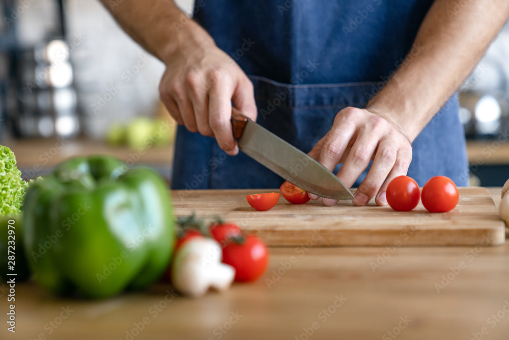 Cropped shot of man cooking on kitchen with vegetables on table Cropped shot of man cooking on kitchen with vegetables on table
