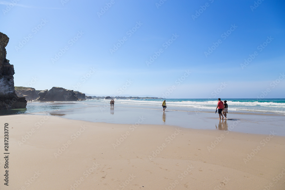 Ribadeo, Spain. Tourists at low tide on the shore of the Atlantic Ocean