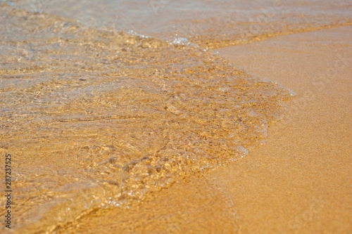 Soft waves with foam of sea on the sandy beach