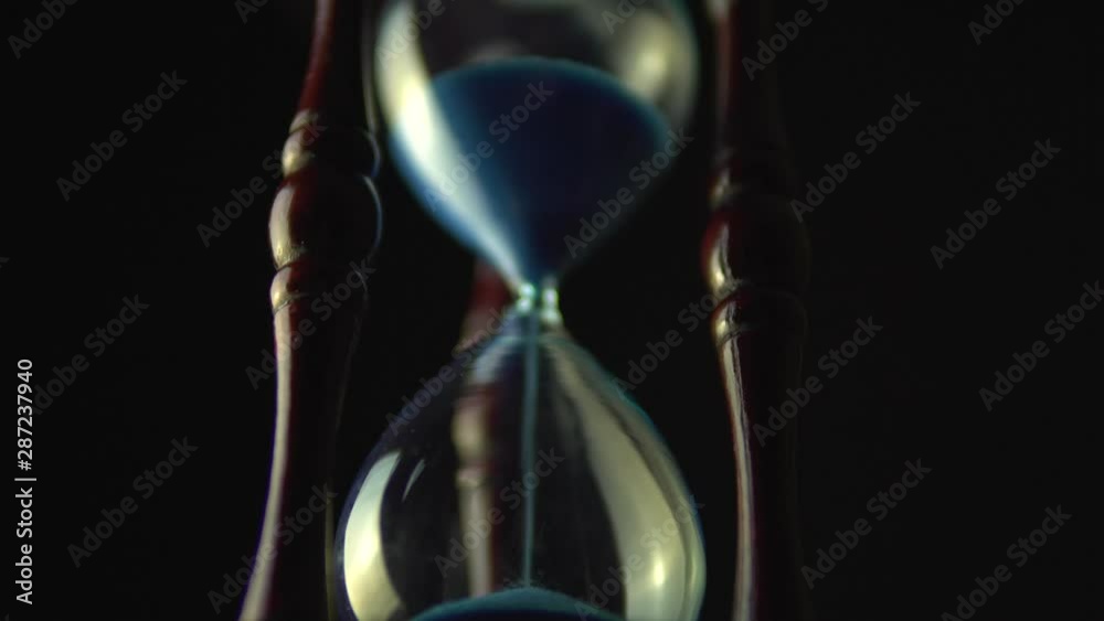 Slow motion rotation of sand timer clock with sand flowing from through