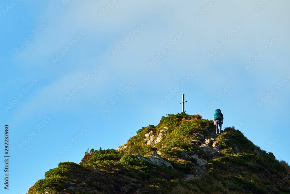 woman climbs to the top of a mountain with a backpack