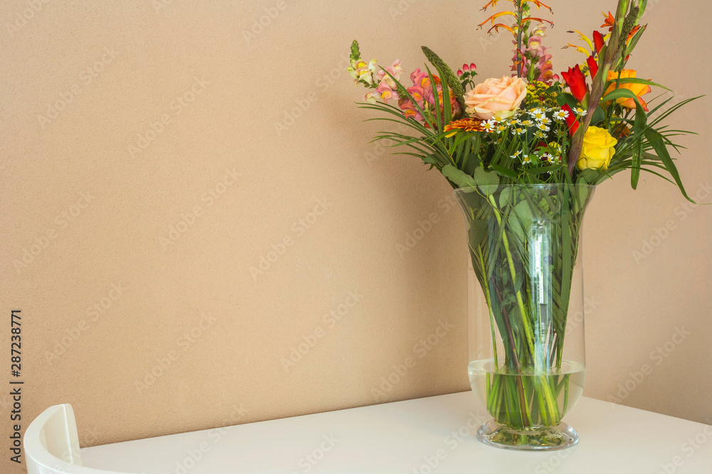 Beautiful flower bouquet on white table with light brown wall, space for text Beautiful flower bouquet on white table with light brown wall, space for text