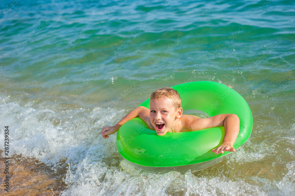 Happy boy swimming and playing at sea with rubber ring