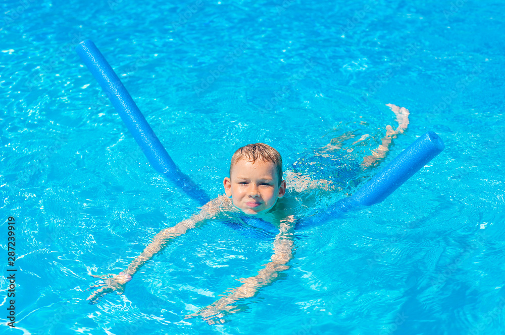 Boy at swimming pool class learning to swim.