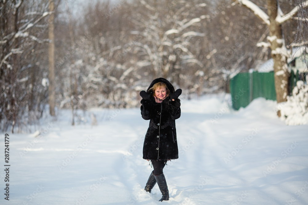 Young woman at winter in the snowy forest or park.