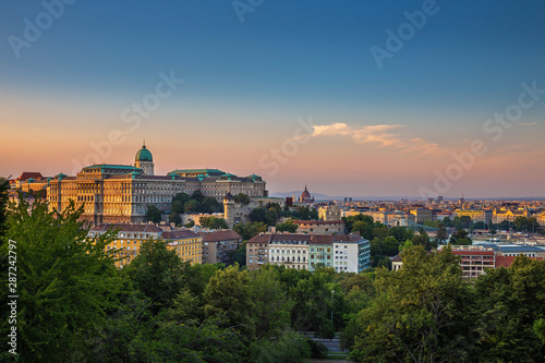 Budapest, Hungary - Buda Castle Royal Palace with a golden sunset and green trees of Buda at summertime with clear blue sky