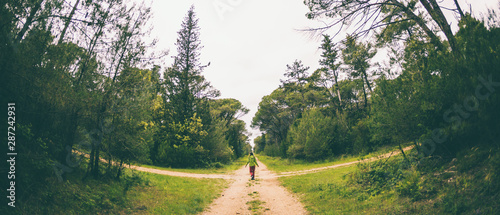 A woman stands at the crossroads of two forest roads.