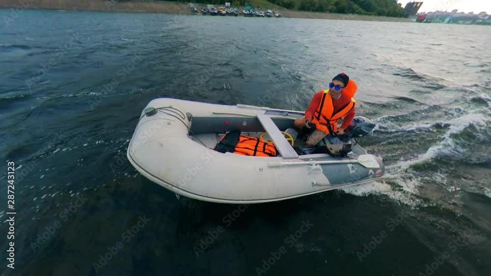Young man riding motorboat on river. Man floats on a motorboat