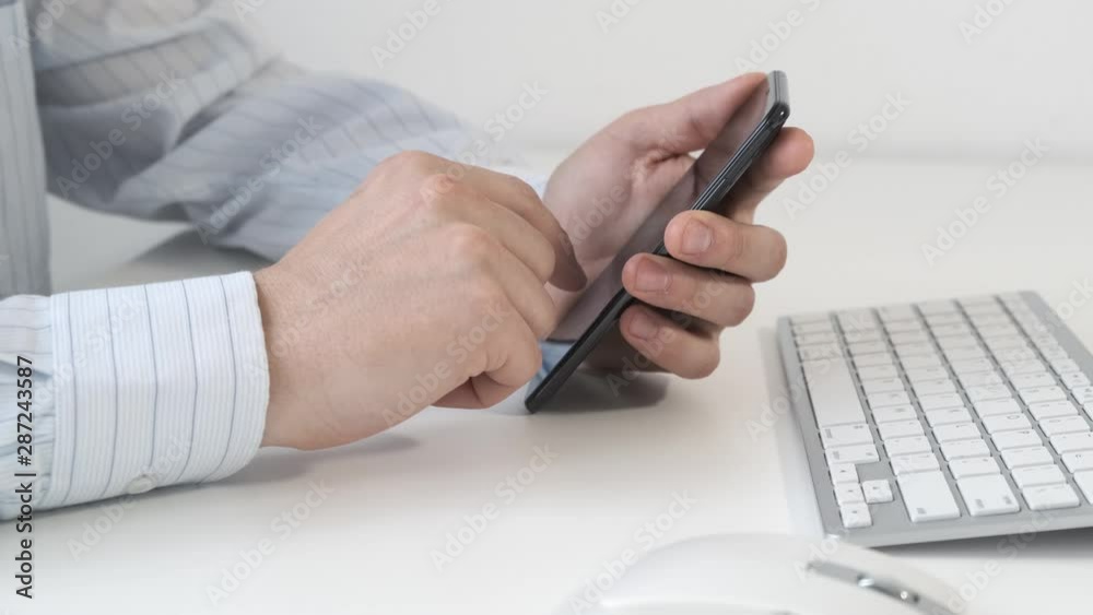 Man holding smartphone in the hand and typing message on working place table. Man holding smartphone in the hand and typing message on working place table.