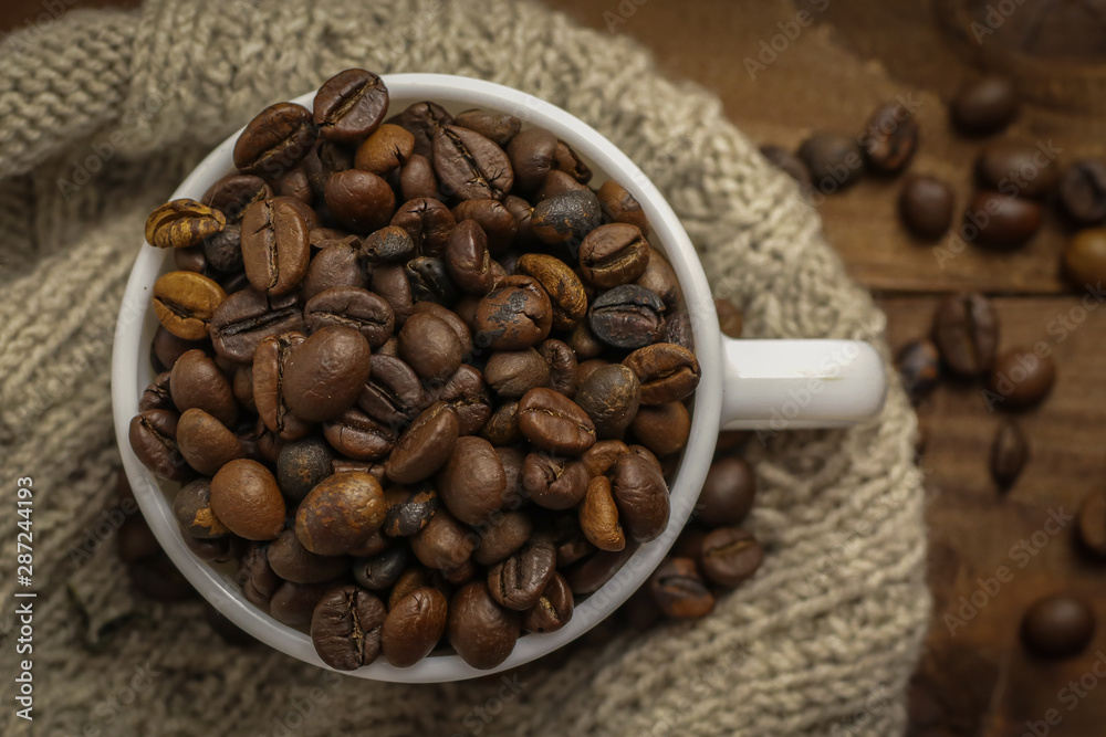 Fototapeta premium Cup with coffee grains on wooden table