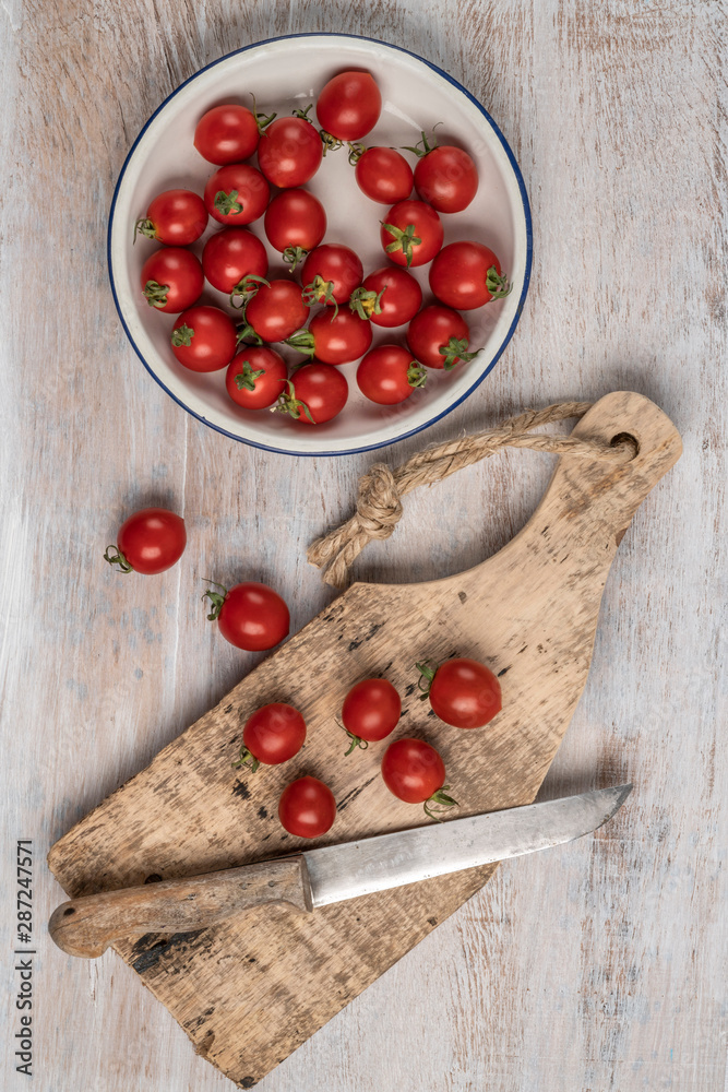 ripe cherry tomatoes and knife on a wooden table