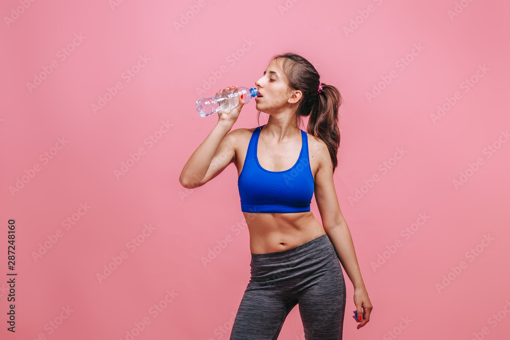sporty girl drinking water on pink background sporty girl drinking water on pink background