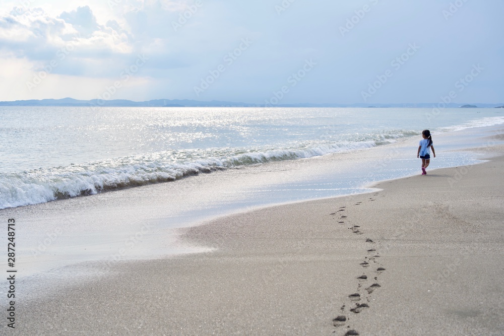 海辺を足跡つけて遠くまで歩く子供