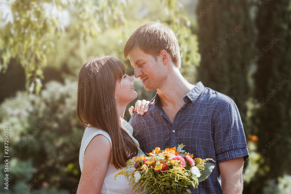A couple of lovers, a love story, a guy and a girl, a bride and groom with a bouquet in their hands kissing. Happy couple on a summer day in the park A couple of lovers, a love story, a guy and a girl, a bride and groom with a bouquet in their hands kissing. Happy couple on a summer day in the park