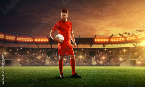 Soccer player in sport uniform ready for the game. Stadium with green grass  tribunes and dramatic night sky