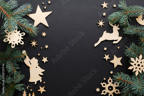 Black Christmas background with handmade wooden decorations and fir tree branches. Christmas holiday celebration, winter, New Year concept. Christmas banner mockup, greeting card template.