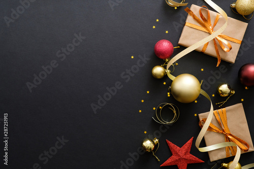 Modern red and golden Christmas decorations, baubles, gift boxes on dark black background. Flat lay design, top view, copy space. Elegant Christmas greeting card mockup.