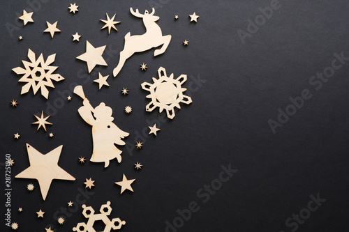 Wooden handmade Christmas decorations on dark black background. Christmas snowflakes, deer, angel, stars with copy space. Flat lay, top view. Winter holidays, Christmas, New Year banner mockup © photoguns