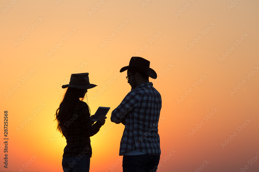 Fototapeta premium Farmers man and woman standing in field at sunset