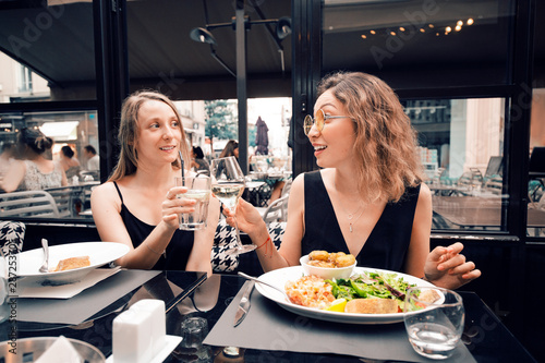 Two female friends celebrating an event and toasting in restaurant