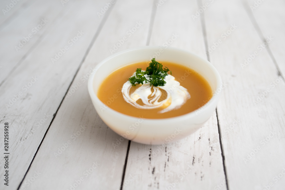 Pumpkin soup with sour cream in white small bowl Pumpkin soup with sour cream in white small bowl