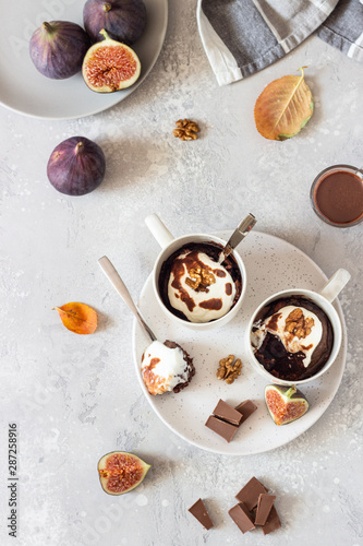 Chocolate mug cupcake with cream cheese or ricotta with caramel sauce in a white ceramic mug on a light grey stone background. Healthy breakfast or dessert. Comfort autumn or winter food. 