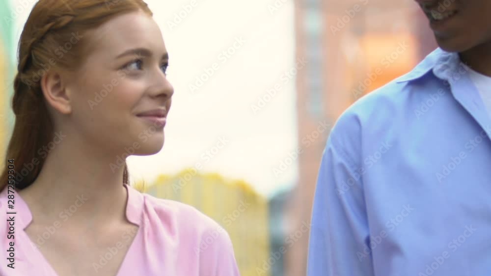 Happy multiracial young couple smiling and walking on city street, romantic date Happy multiracial young couple smiling and walking on city street, romantic date