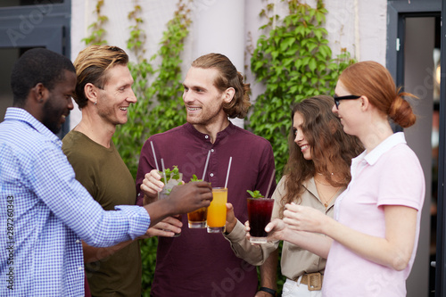 Multi-ethnic group of people enjoying cold drinks and chatting cheerfully during outdoor Summer party  copy space
