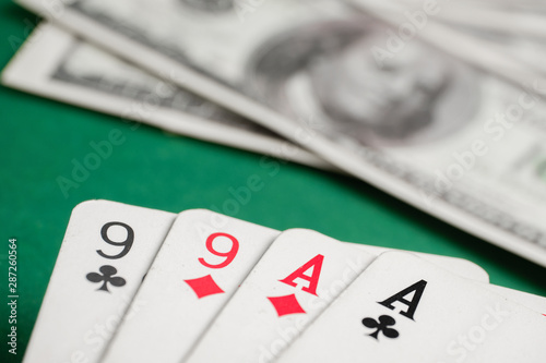 Two pair of aces and nines during poker with dollars on green table.