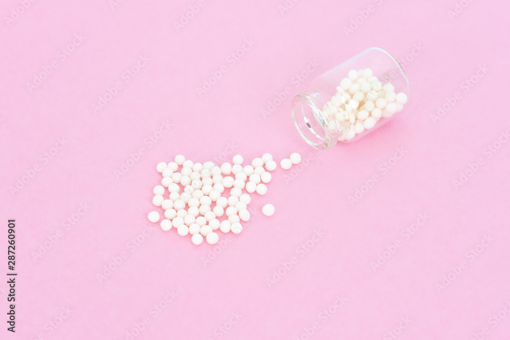 Homeopathy eco medicine concept - classical homeopathy pills in vintage glass bottles on pink background. Flatlay. Top view. Copyspace