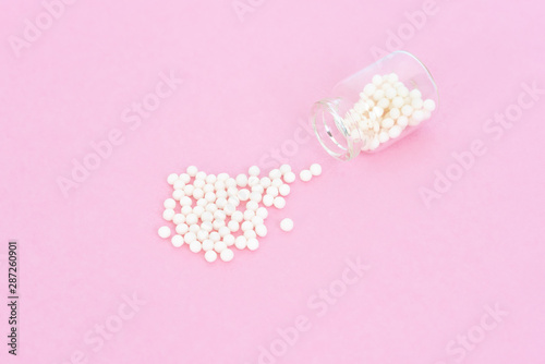 Homeopathy eco medicine concept - classical homeopathy pills in vintage glass bottles on pink background. Flatlay. Top view. Copyspace © Juliaap