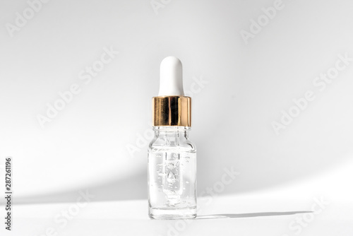 Anti aging serum in glass bottle with dropper on white background. Facial liquid serum with collagen and peptides. Skincare essence for beautiful healthy skin. 