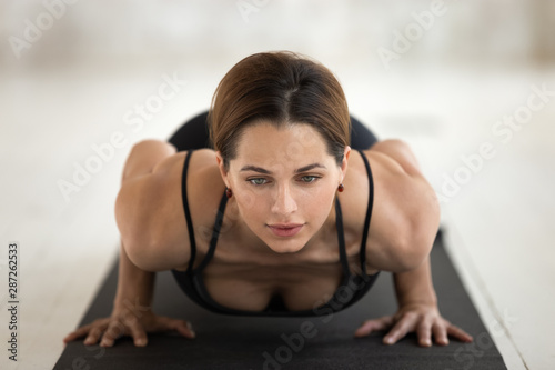 Young woman practicing yoga, chaturanga dandasana pose close up