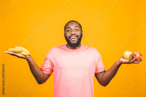 Diet concept. Healthy african american black man holding fruits isolated against yellow background.